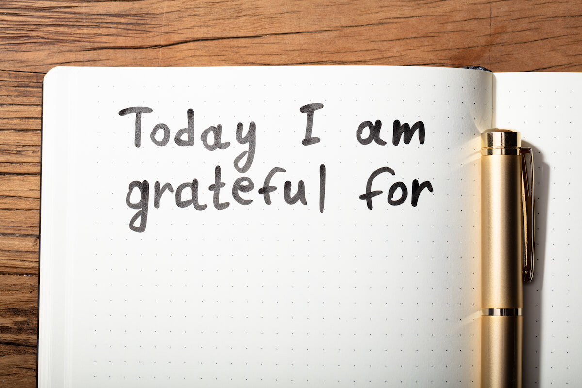 Close-up Of Gratitude Word With Pen On Notebook Over Wooden Desk-Power of gratitude