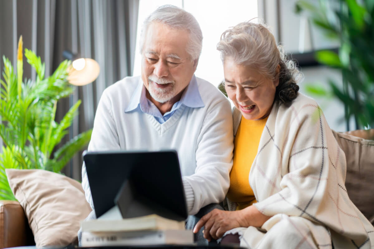 Older Asian Couple Looking at Tablet, Smiling