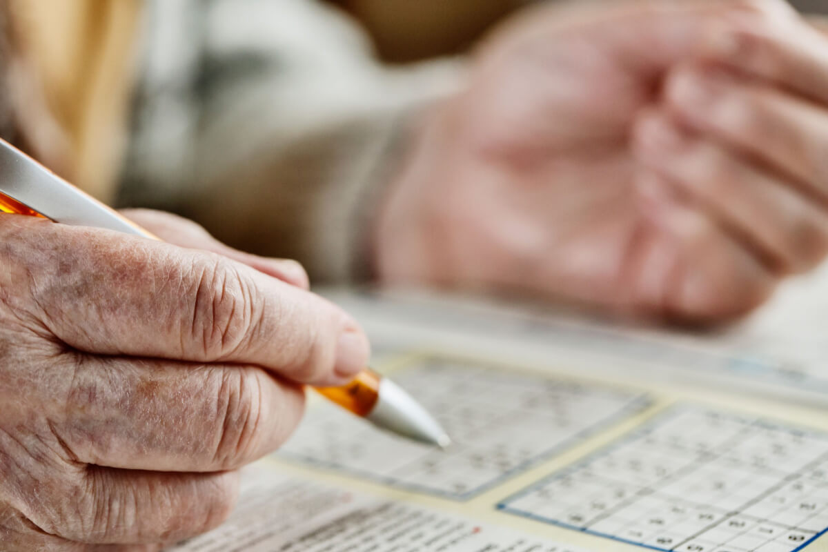 Close up of older adults completing Sudoku puzzles