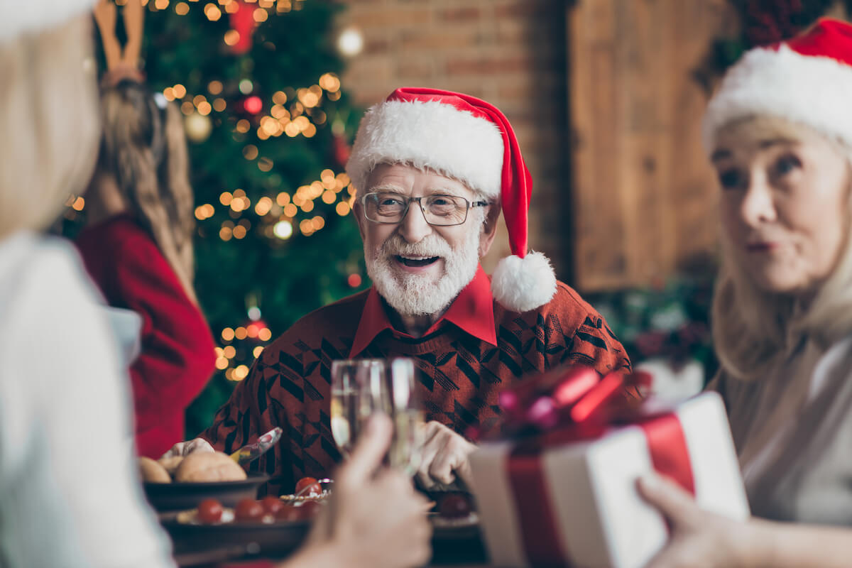 Grandfather positive cheerful smiling in eye glasses spectacles wearing santa hat