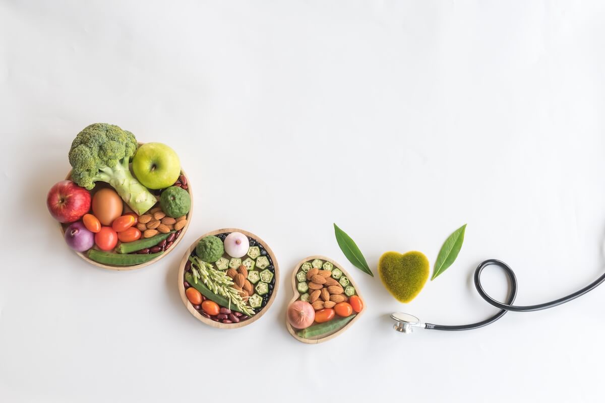 Heart health-Organic healthy food in wooden bowls,medical stethoscope and green heart shape on white background for the health concept