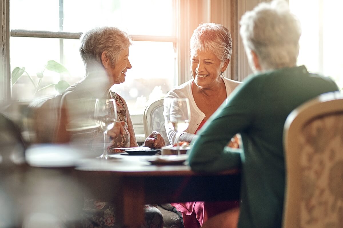 Senior women, friends and smile in restaurant for wine, vacation and retirement together with happy. Elderly people, reunion and relax in diner for drinks, holiday and social celebration with memory Senior Living Social Events